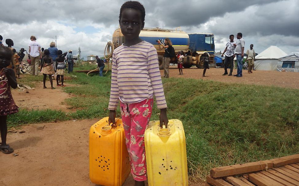 Wasser im Südsudan: Ein Kind trägt Wasserkanister zu einem Bohrloch