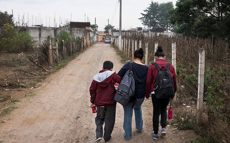 Eine unbefestigte Straße in Guatemala: Eine Mutter bringt ihre beiden Kinder zur Schule
