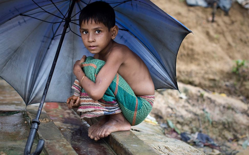 Monsun im Flüchtlingslager: Ein Rohingya-Mädchen sucht unter Regenschirm Schutz vor den Regenfällen