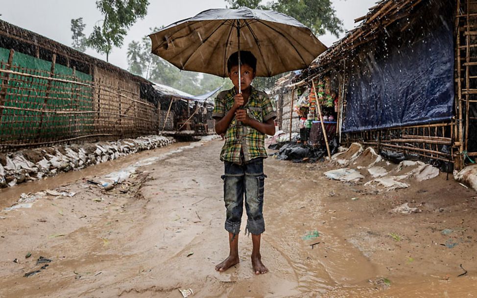 Rohingya: Ein Junge steht im Flüchtlingscamp unter einem Schirm
