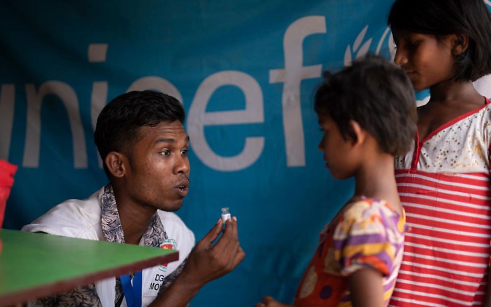 Monsun in Bangladesch: UNICEF-Helfer erklärt Kindern Cholera-Impfung