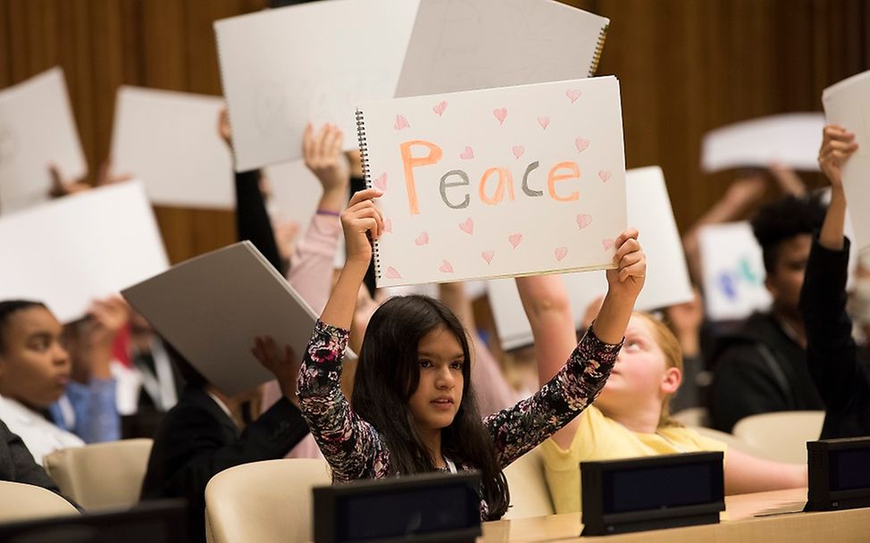 Ohne Angst für Menschenrechte und Demokratie: Mädchen hält Friedensbotschaft hoch