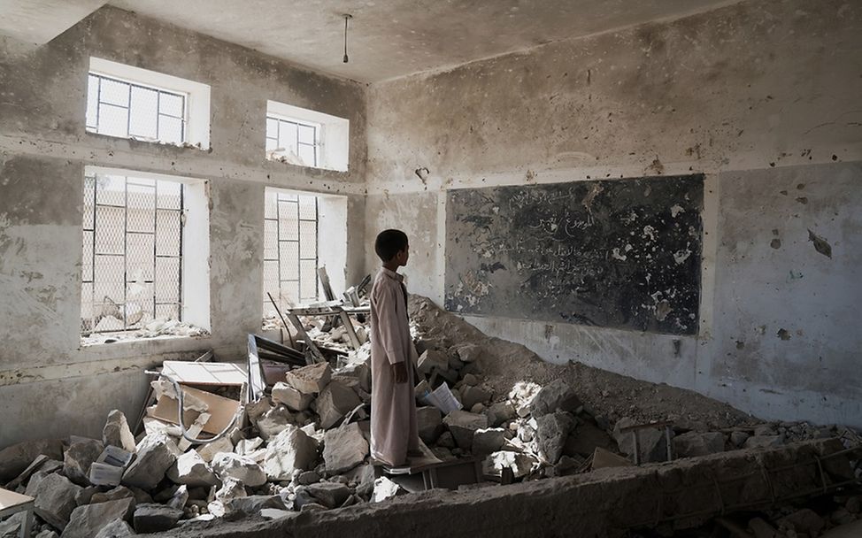 Junge inmitten der Trümmer seines ehemaligen Klassenzimmers