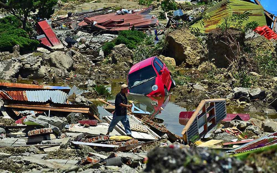 Ein Mann inmitten von Trümmern, die der Tsunami hinterlassen hat. 