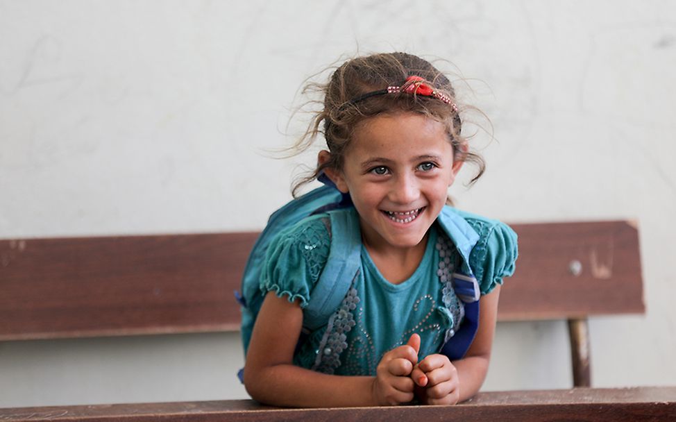 Idlib, Syrien: Ein Mädchen sitzt lachend auf einer Bank.