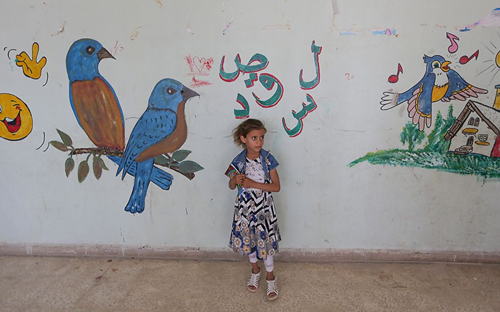 Idlib, Syrien: Ein Mädchen steht unsicher vor einer bemalten Wand.