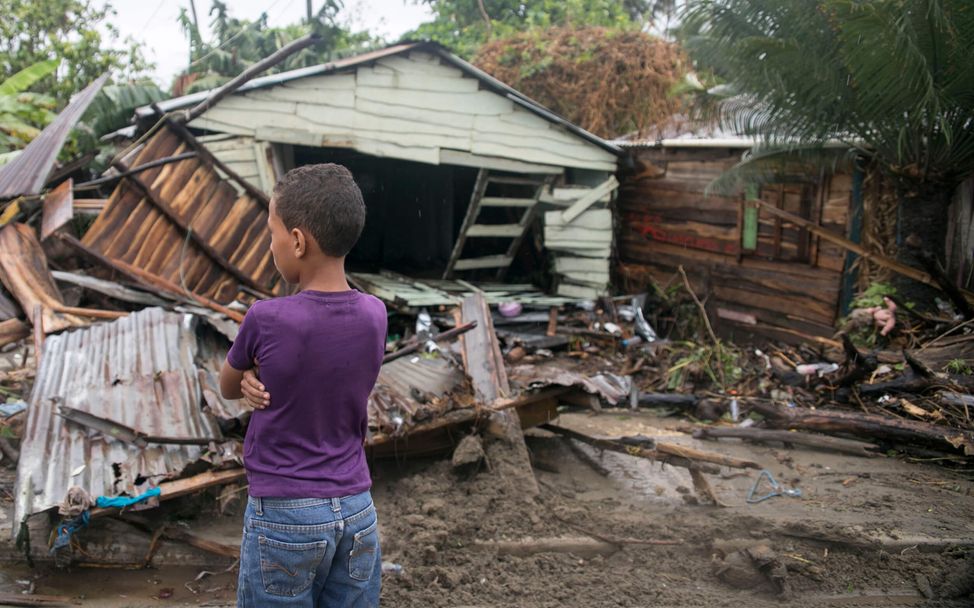Spenden Weihnachten: Junge steht vor vom Hurrikan Irma zerstörten Häusern