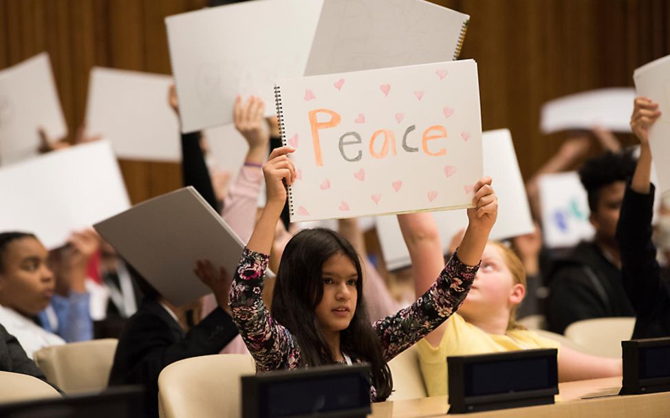 Kinderrechte: Kinder halten auf einer Konferenz Schilder hoch