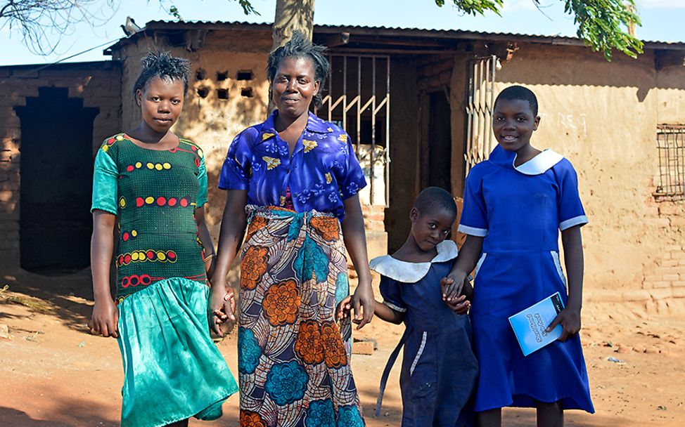 Malawi: Aness mit ihren beiden Schwestern und ihrer Mutter vor ihrem kleinen Haus.