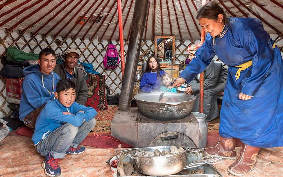 Eine Mutter in einer mongolischen Jurte kocht für ihre Familie. 