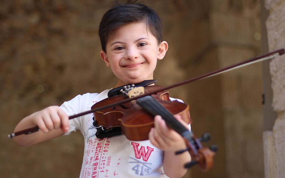 UN-Kinderrechtskonvention: Ein 8-jähriger Junge mit Downsyndrom spielt Geige.