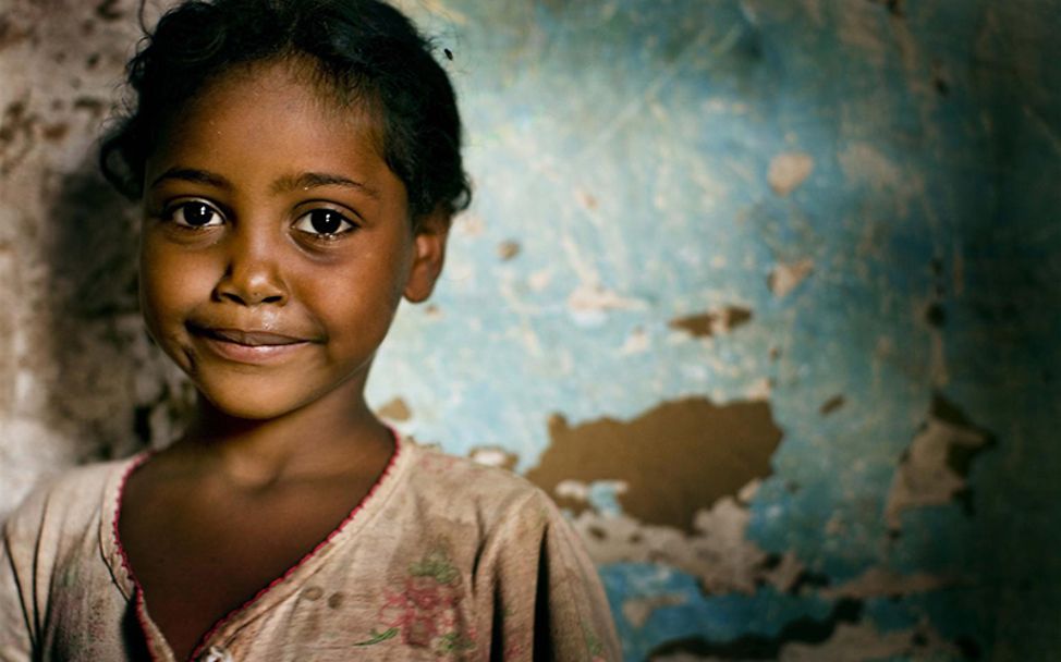 UN-Kinderrechtskonvention: Ein junges Mädchen steht vor einer Weltkarte.