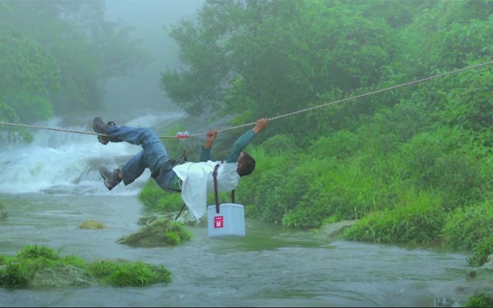 Indien: Ein UNICEF-Helfer transportiert Impfstoffe über einen Fluss