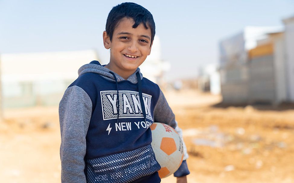 Za'atari: Der zehnjährige Diaa mit einem Fußball unter dem Arm lächelt.