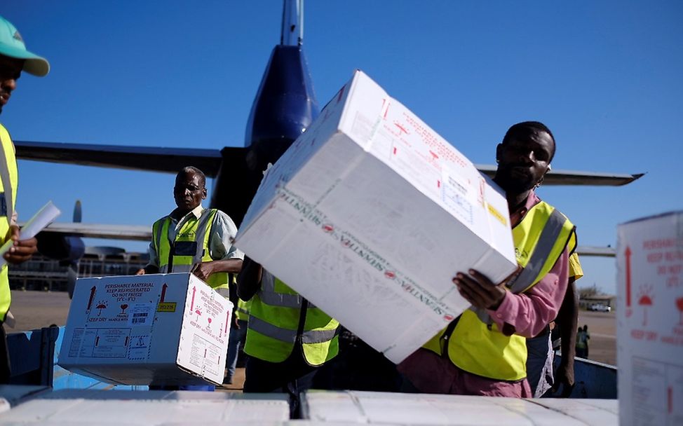 Männer laden die Kisten mit Cholera-Impfstoffen aus einem Flugzeug aus.