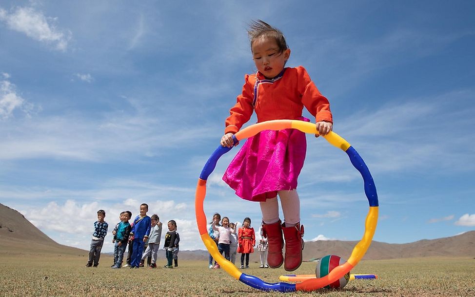 Mongolei: EIn Mädchen spielt mit einem Reifen