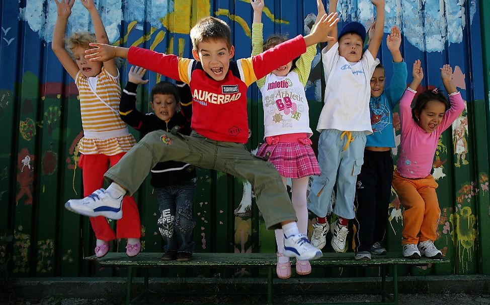 Child Friendly Cities Summit: Kinder springen vor blauer Wand