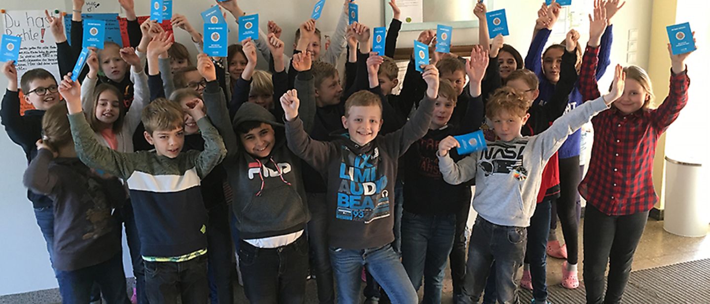 Schüler der Overbergschule Rhede zeigen ihre Kinderrechtepässe.