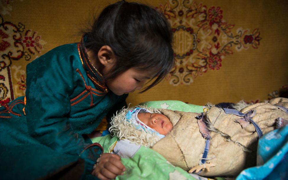 Mütter in aller Welt: Ein Mädchen aus der Mongolei betrachtet seine neugeborene Schwester