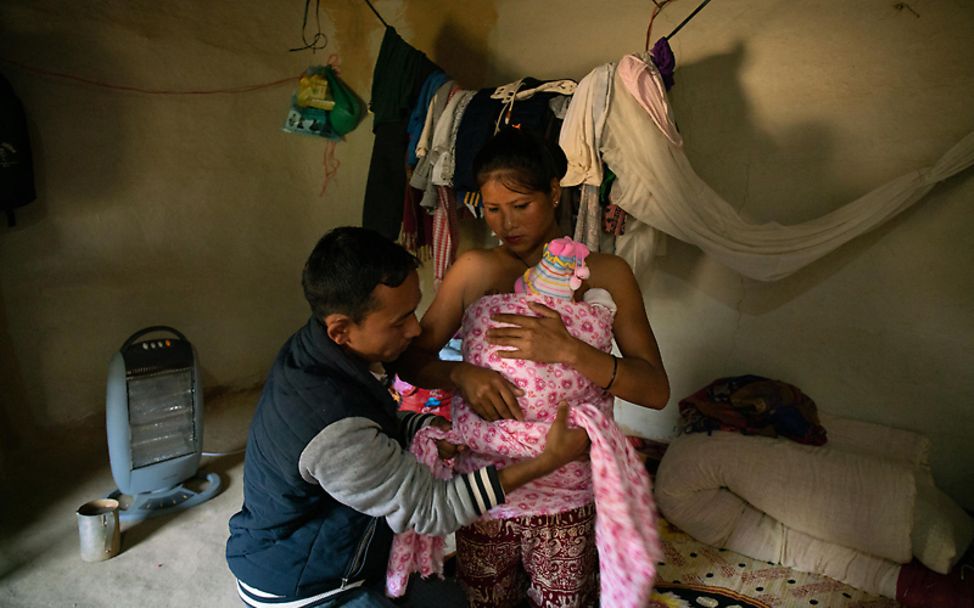Mütter in aller Welt: Ein Vater hilft seiner Frau, ihr Baby in ein Tuch zu binden