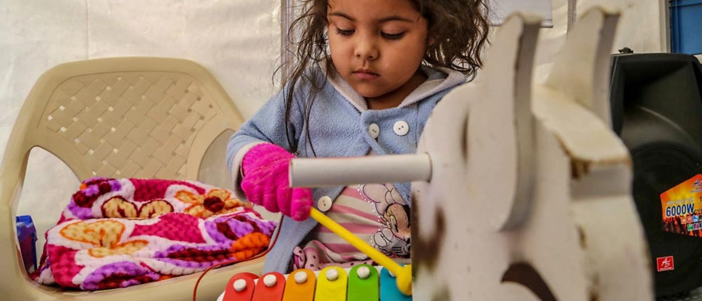 Ein Mädchen spielt in einem UNICEF-Zelt Xylophon. 