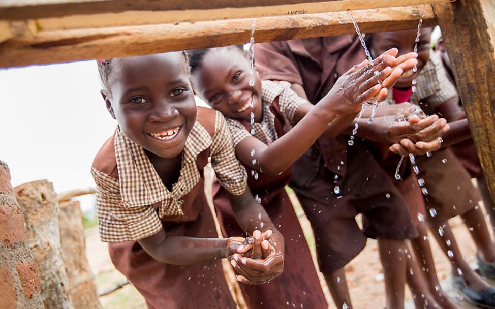 Sauberes Wasser: Mädchen waschen sich die Hände an einem Brunnen