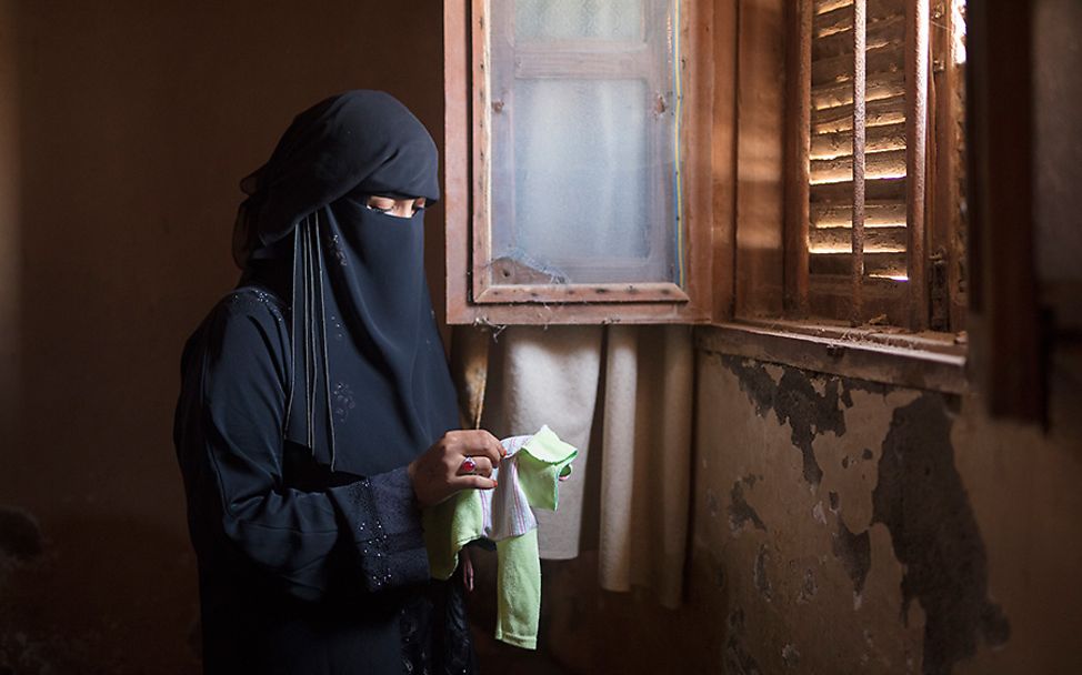 Jemen: Yasmin hält die Kleidung ihres verstorbenen Kindes in den Händen.