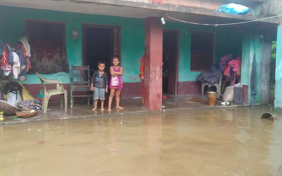 Nepal: Zwei Kinder stehen vor dem überfluteten Vorhof ihres Hauses.