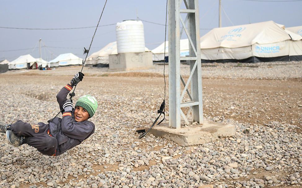 Irak: Ein Junge in Winterkleidung spielt an einem Seil im Flüchtlingscamp.