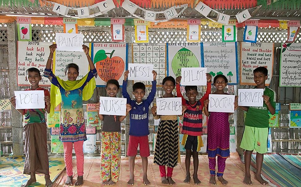 Bangladesch: Acht Kinder halten Blätter mit ihren Berufswünschen darauf hoch.