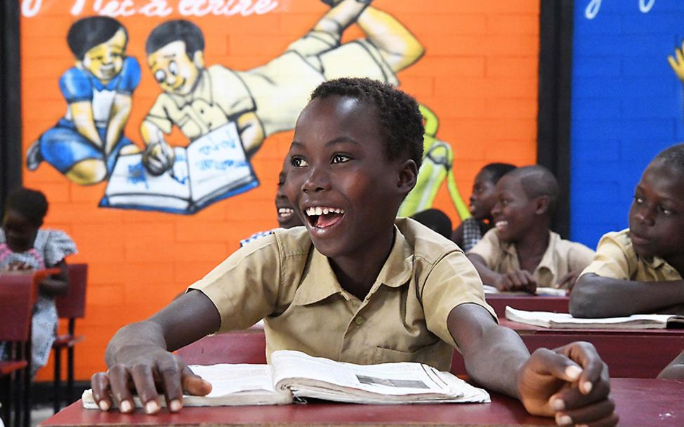 Elfenbeinküste: Ein lachender Junge sitzt in der neu errichteten Recyclingschule.