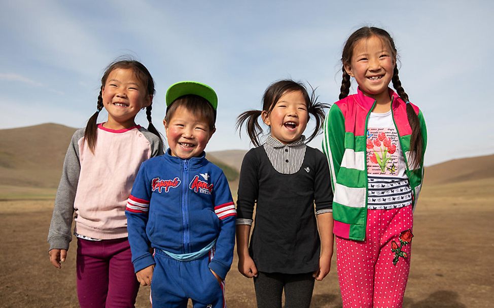 Mongolia: Drei Mädchen und ein Junge blicken lachend in die Kamera.
