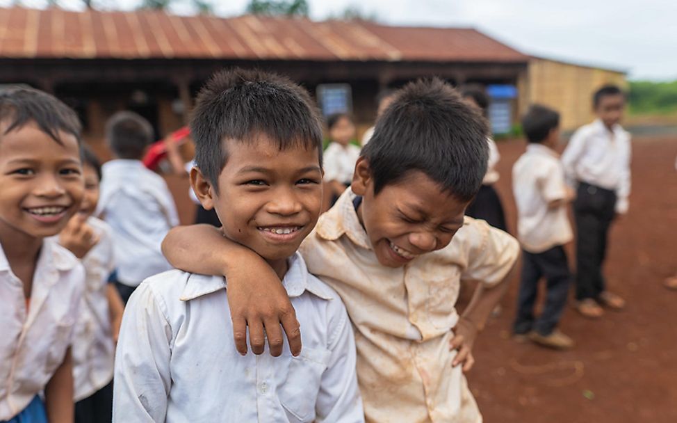 Kambodscha: Drei Jungen albern auf dem Schulhof herum.