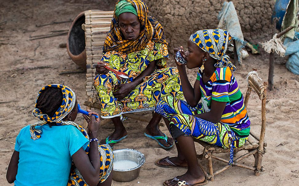 Mali: Fatoumata frühstückt mit ihrer Mutter und einer ihrer Schwestern Hirsebrei im Freien.
