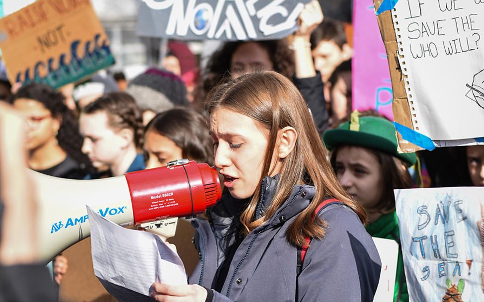 klimawandel folgen kinder: Ein Mädchen spricht bei einer Demo in ein Megaphon.