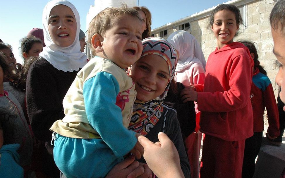 Za'atari-Camp/Jordanien: Ein Mädchen hält einen weinenden Jungen auf dem Arm (© UNICEF/2013/Schneider)