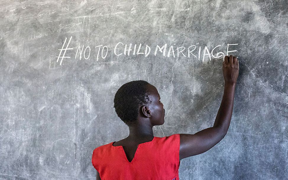 Uganda: Faida schreibt #no to child marriage an eine Schultafel.