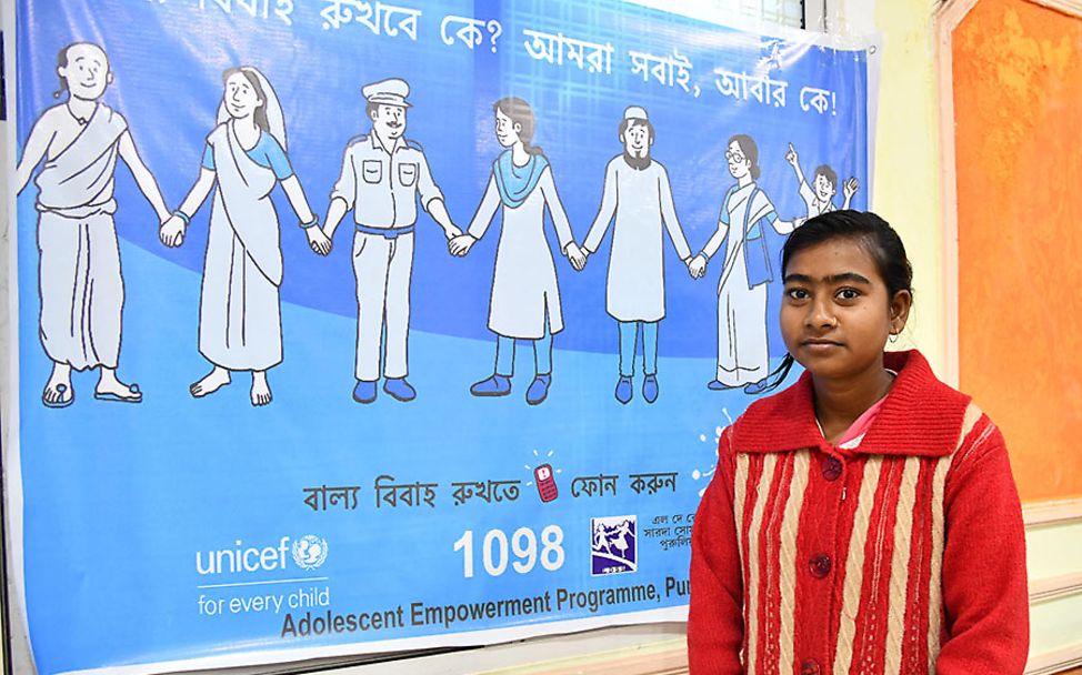 Indien: Die 16-jährige Maina steht vor einem UNICEF-Plakat.