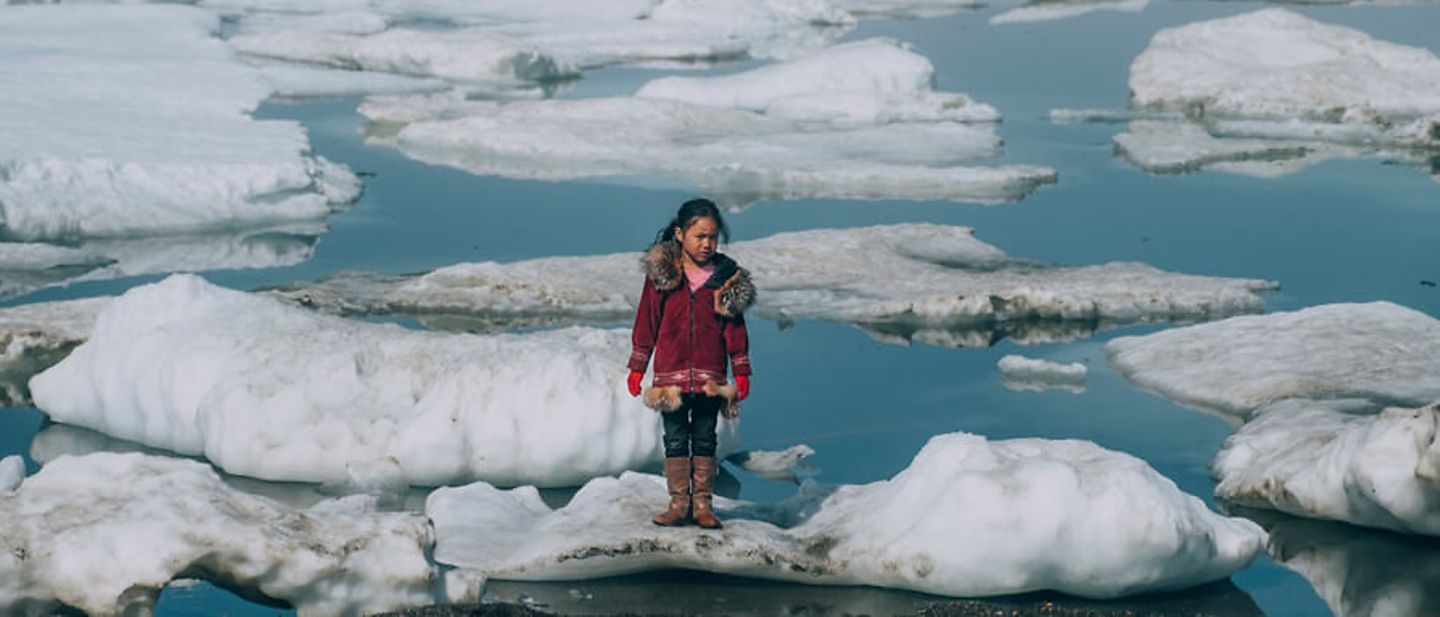 Spenden Klimaschutz: Ein Mädchen in Alaska steht auf einer durch Erderwärmung kleiner gewordenen Eisscholle. 