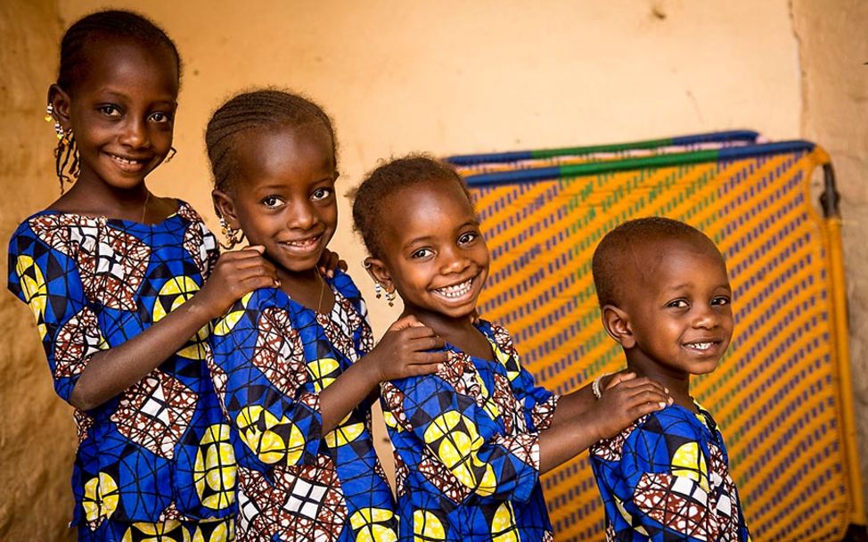 Sterblichkeit unter Säuglingen und Kindern verbessern: Vier Schwestern in Mali stehen lachend hintereinander.