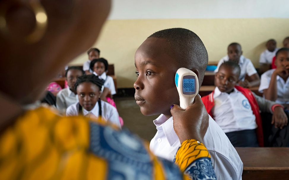 Ebola-Bekämpfung: Eine Frau misst per Fieberthermometer die Temperatur bei einem Schulkind.