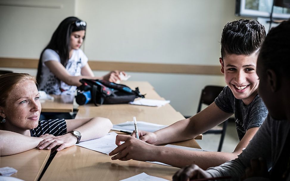 Deutschland: Drei Schüler lernen zusammen mit ihrer Lehrerin.
