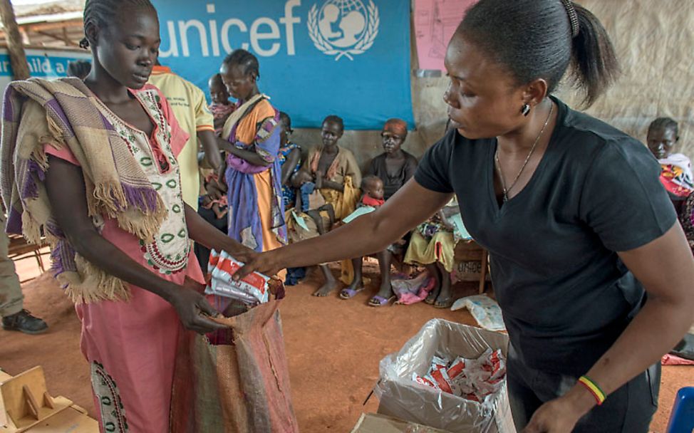 Südsudan: Im Ernährungszentrum gibt eine Helferin Erdnusspaste an die Mütter aus
