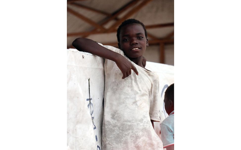 Mosambik: Ein Kind steht an ein Banner gelehnt.