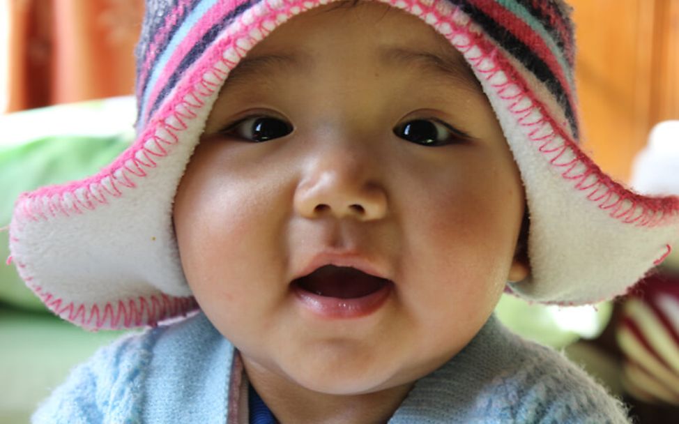 Bhutan: Süßes Baby mit Mütze lacht