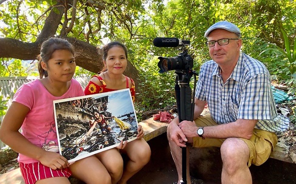 Philippinen: Hartmut Schwarzbach zeigt Wenie und ihrer Mutter das Siegerbild 2019.