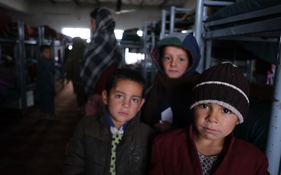 Afghanistan: Drei Jungen stehen in einem dunklen Schlafsaal eines Waisenhauses.