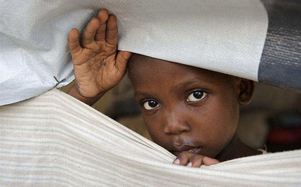 Ein Mädchen schaut aus einer Notunterkunft. Ihr Zuhause wurde von dem Erdbeben zerstört.
