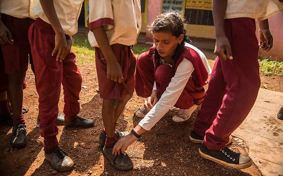 Indien: Kusma hilft einem jüngeren Schüler beim Schuhebinden.