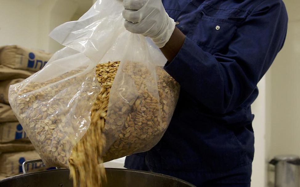 Sudan: In einer Erdnusspaste-Fabrik schüttet ein Mitarbeiter Erdnüsse in einen Trichter